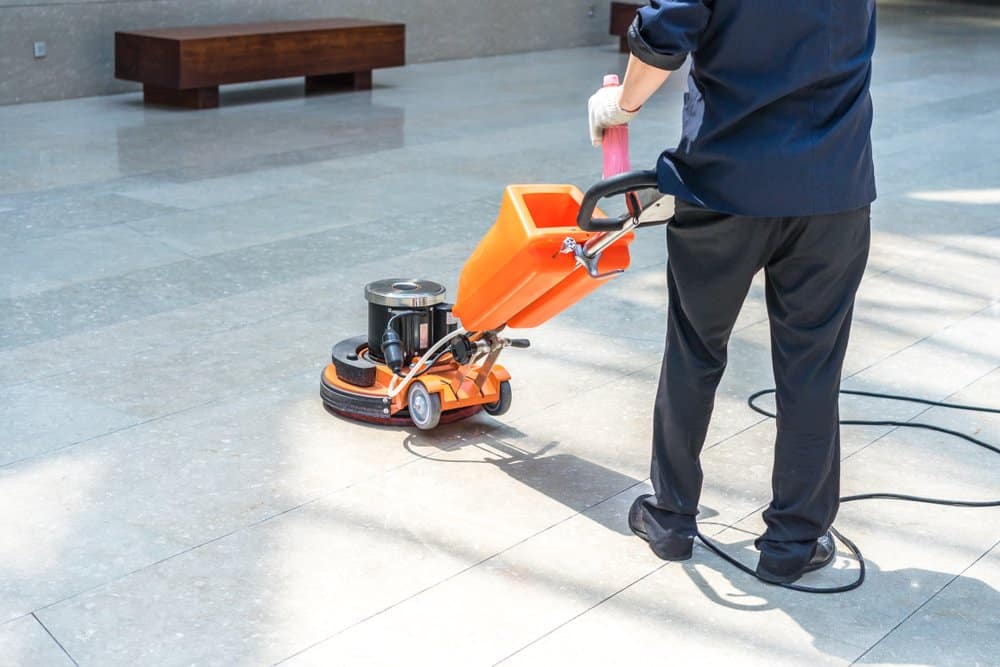 floor cleaning technician machine scrub cleaning a hard floor surface