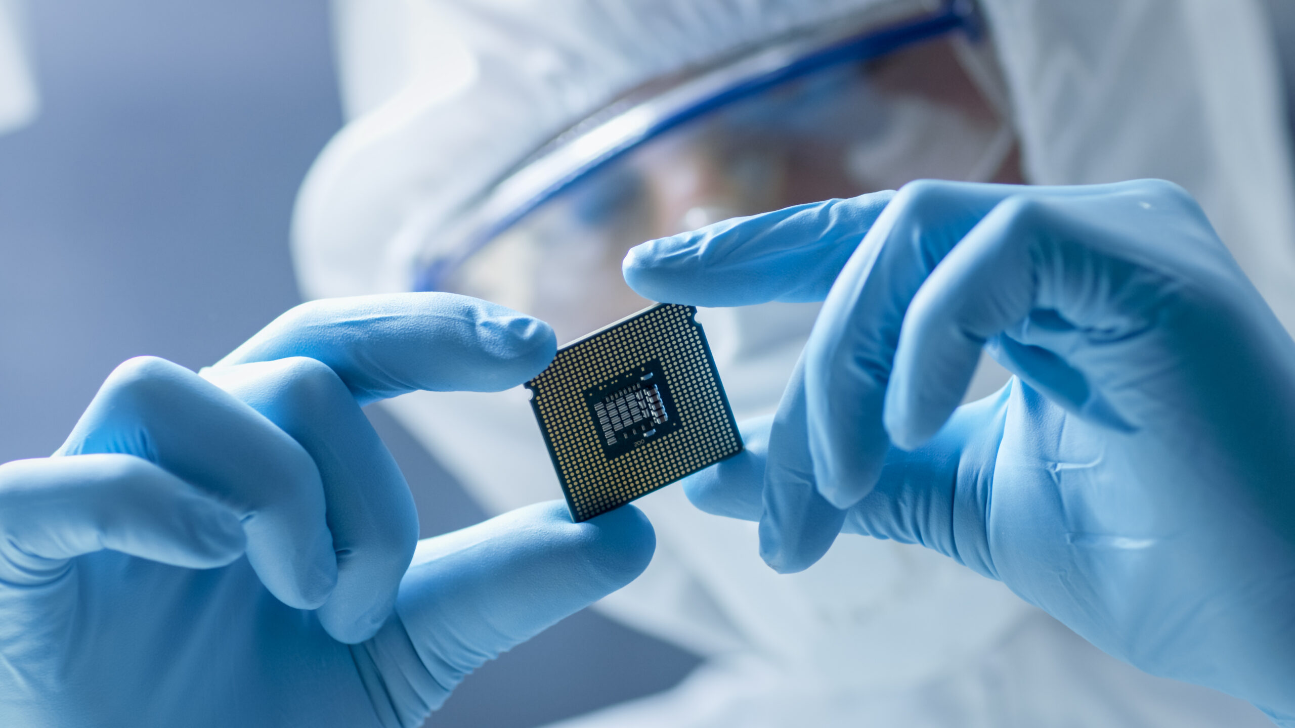 Worker in protective gear inspecting electronic chip